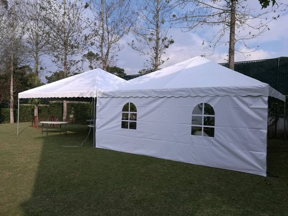 Carpas blancas con paredes y ventanas en un jardín