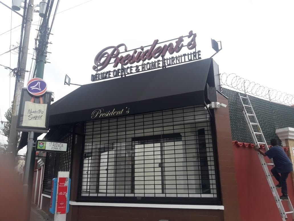 Cenefa negra con nombre impreso en la fachada de una tienda